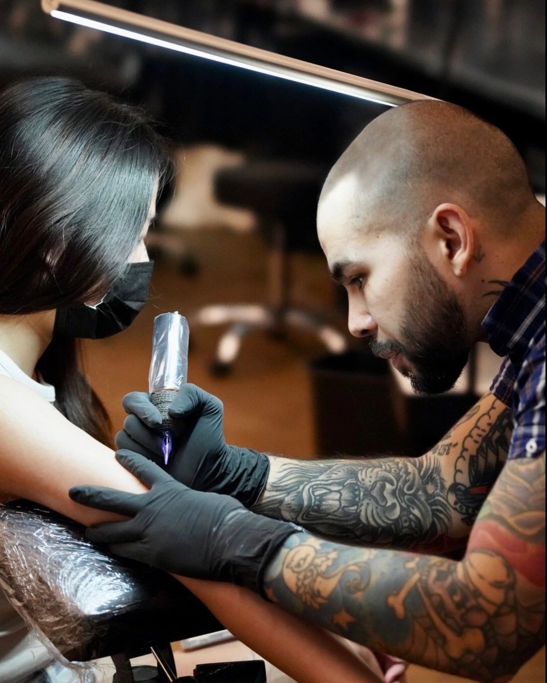 JD applying fine line tattoo ink to a client arm in the studio